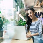 Mujer trabajando en cafeteria con portatil