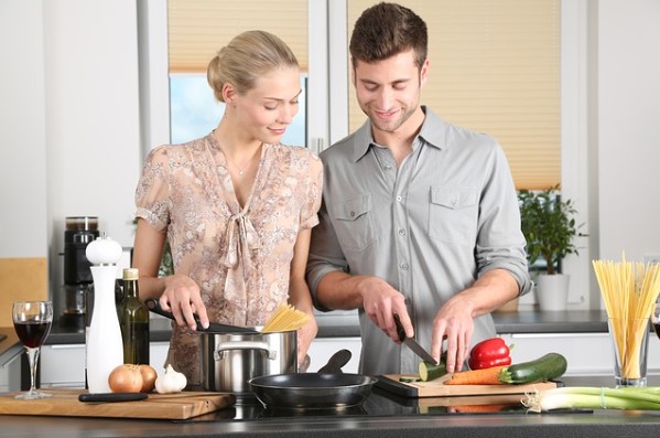 Pareja cocinando pasta con verduras