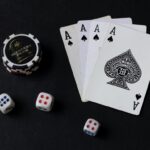 Cartas, dados y fichas de casino sobre fondo negro