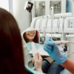 Chica sonriendo en espejo en clinica dentista