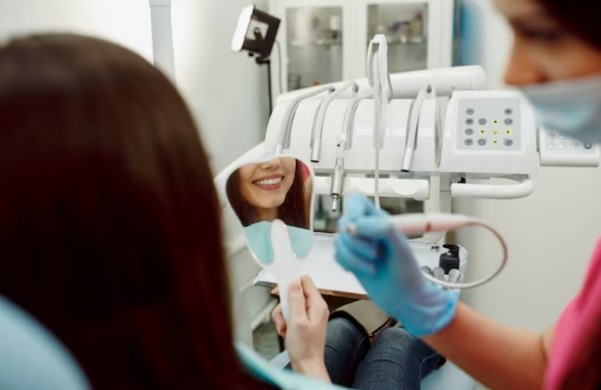 Chica sonriendo en espejo en clinica dentista