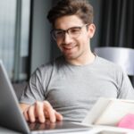 Chico trabajando feliz con ordenador portatil