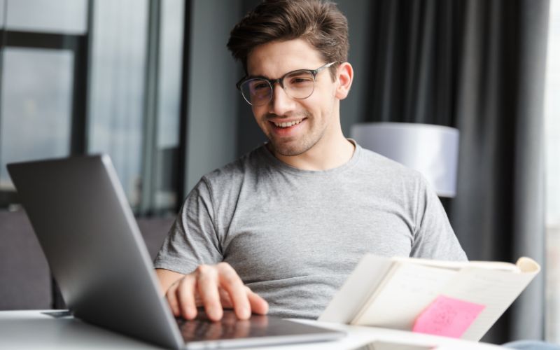 Chico trabajando feliz con ordenador portatil